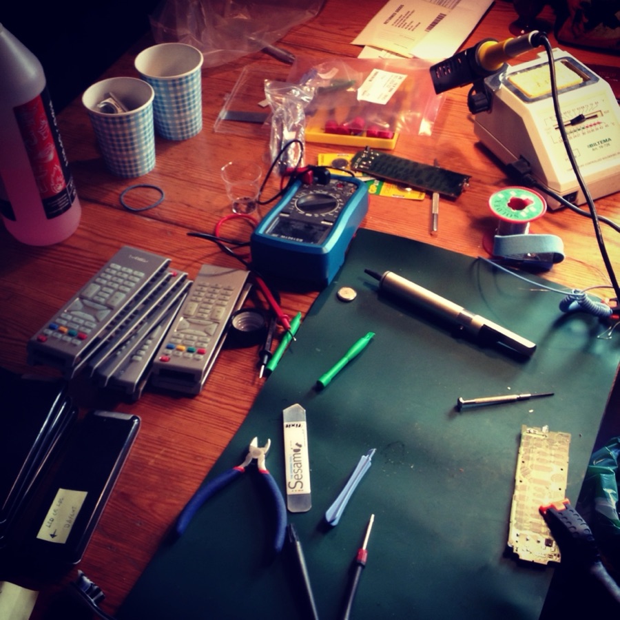 Reparasjonsbord med multimeter, fjernkontroller og elektronikk-deler